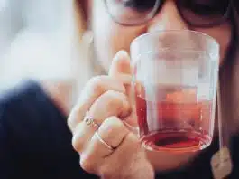 woman holding clear drinking glass with red liquid