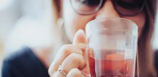 woman holding clear drinking glass with red liquid