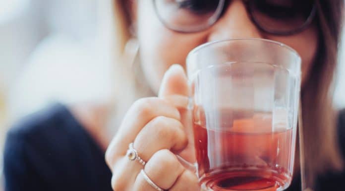 woman holding clear drinking glass with red liquid