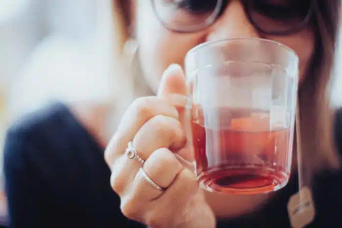 woman holding clear drinking glass with red liquid